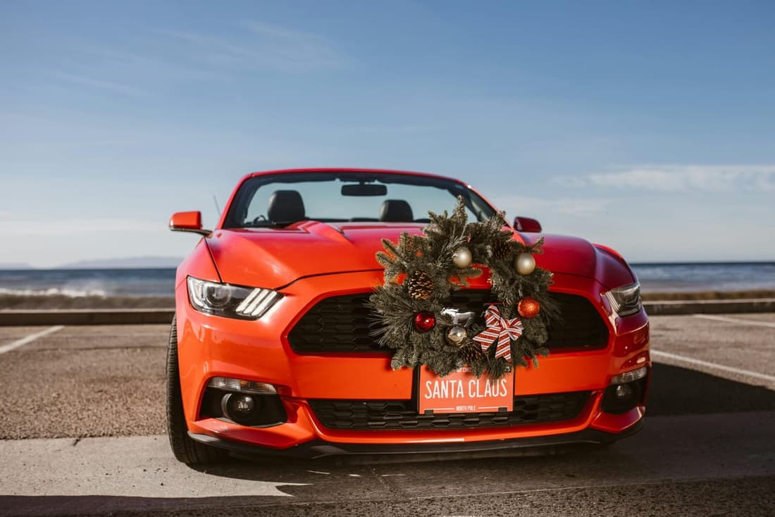 Red Ford Mustang with a Christmas wreath on the grille and a “Santa Clause” license plate, freshly detailed by Premier Detailing in West Plains, MO.