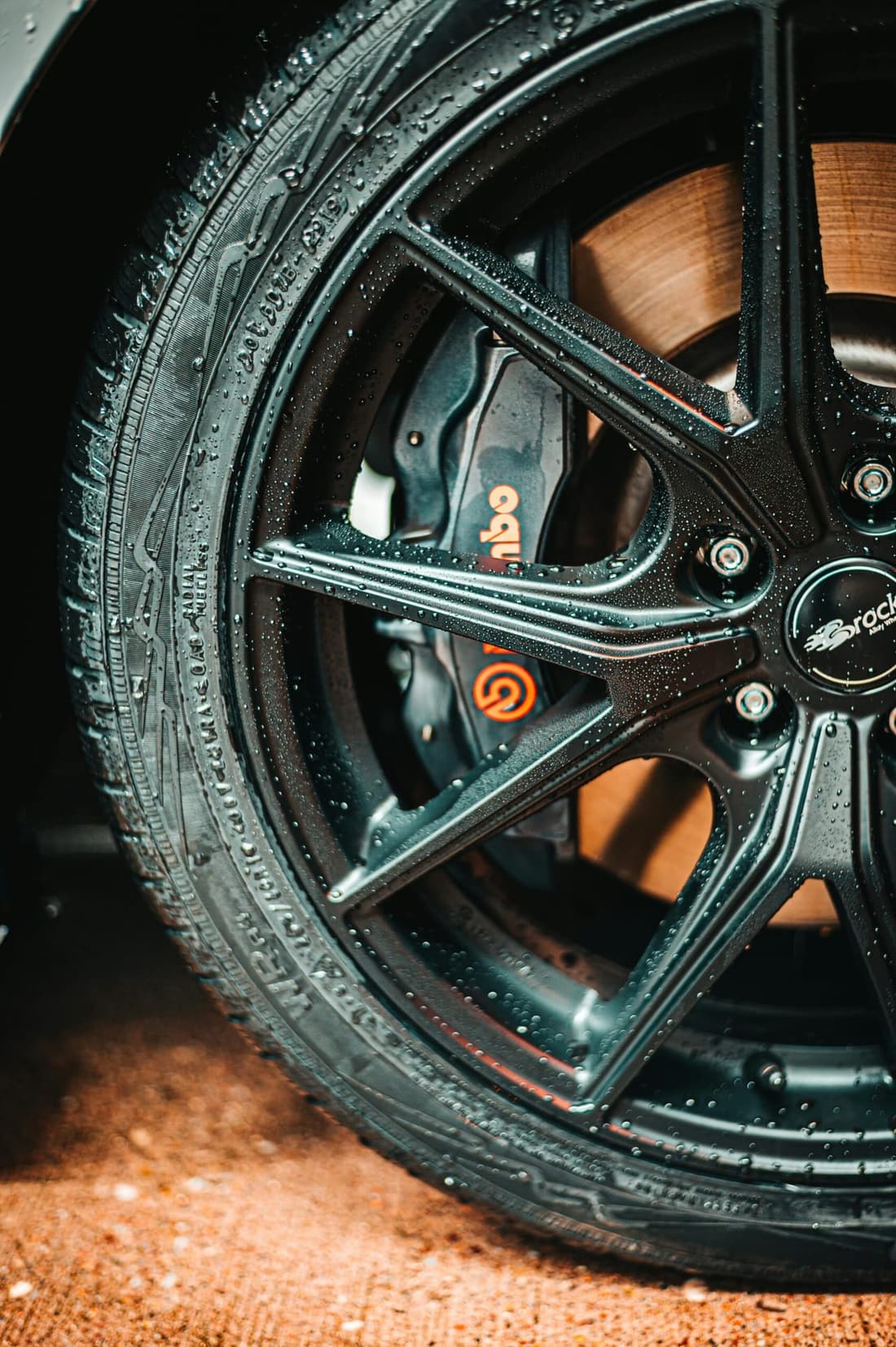 "Close-up of a wet car wheel featuring sleek rims and Brembo brake calipers, showcasing the premium detailing results from Premier Detailing in West Plains, MO."