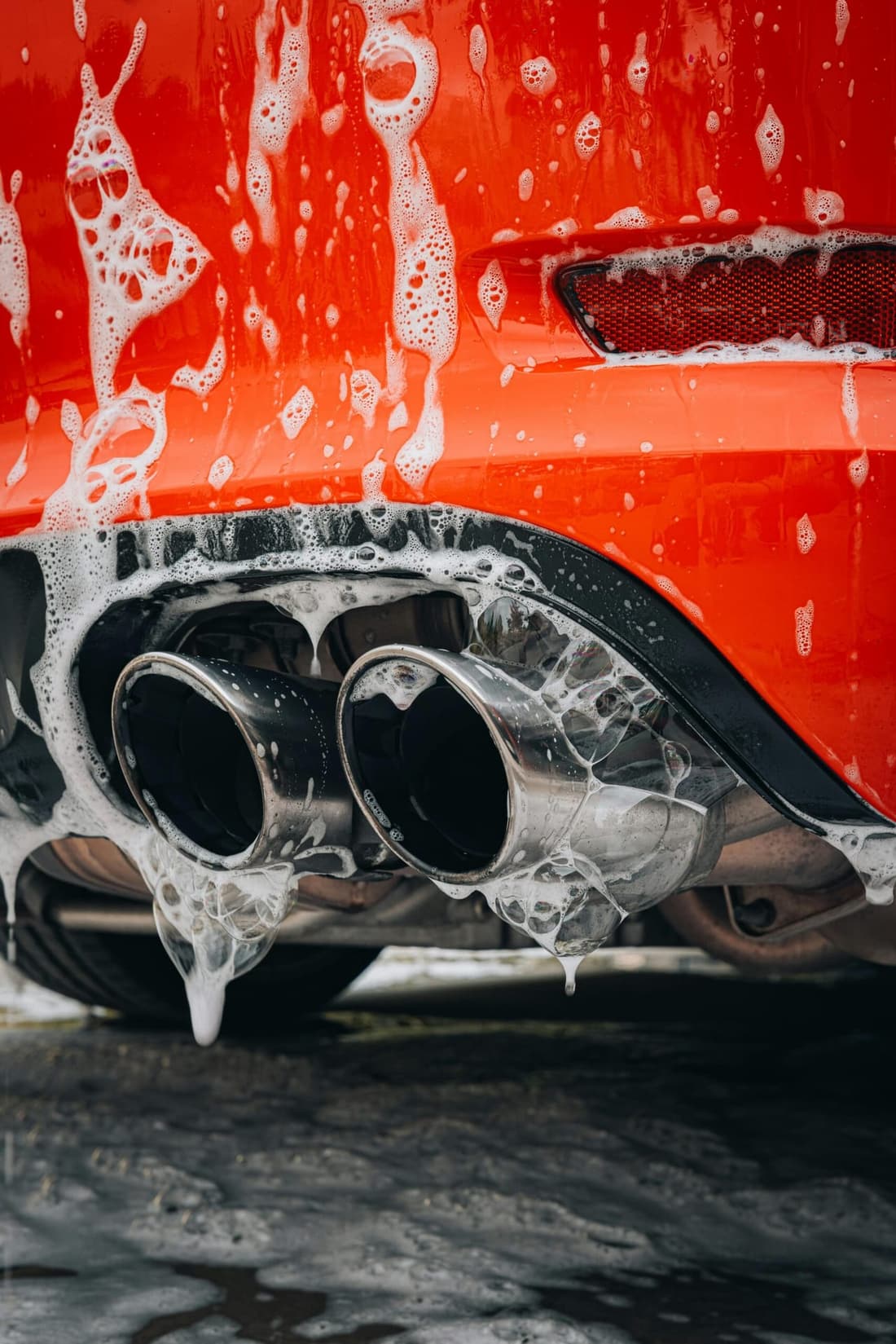 Bottom view of a soapy car exhaust during a professional detailing session by Premier Detailing in West Plains, MO.