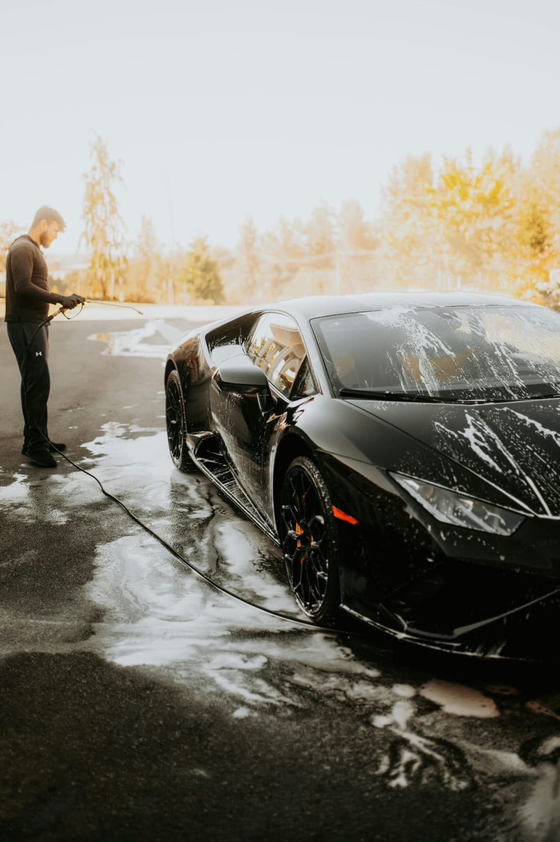 Mobile car detailing professional washing a luxury black sports car with foam at home in West Plains, MO – Premier Detailing