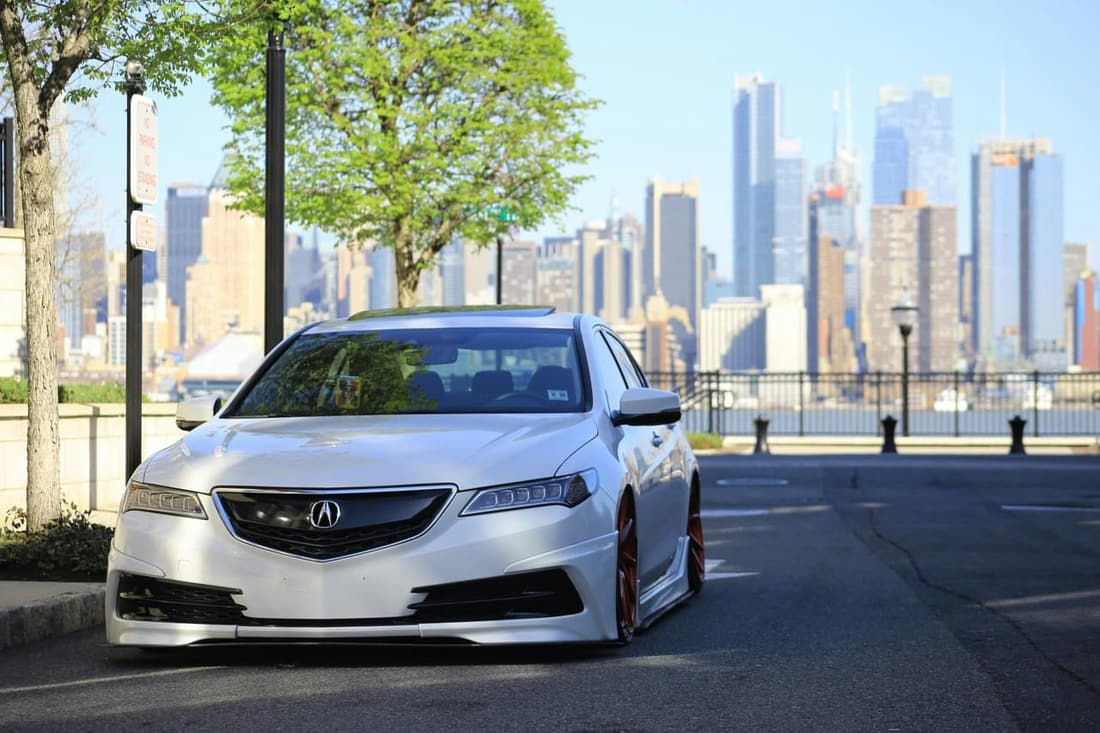 Sleek silver Acura sedan freshly detailed, parked in front of a city skyline on a sunny spring day in West Plains MO