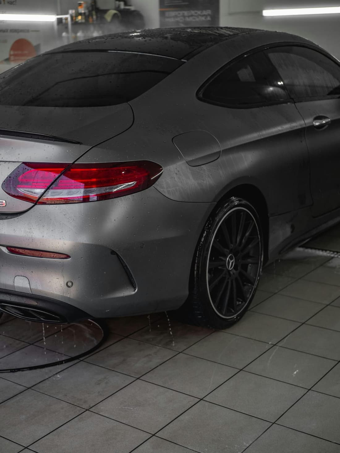 A sleek, matte-gray Mercedes-Benz coupe with water droplets on its surface after a professional car wash.
