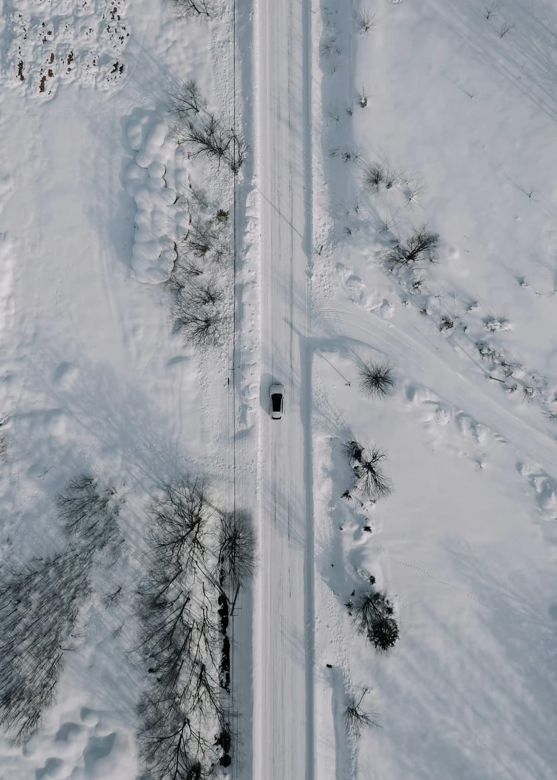 "A car driving through a snow-covered road, highlighting the need for winter detailing services from Premier Detailing to protect and maintain its condition."