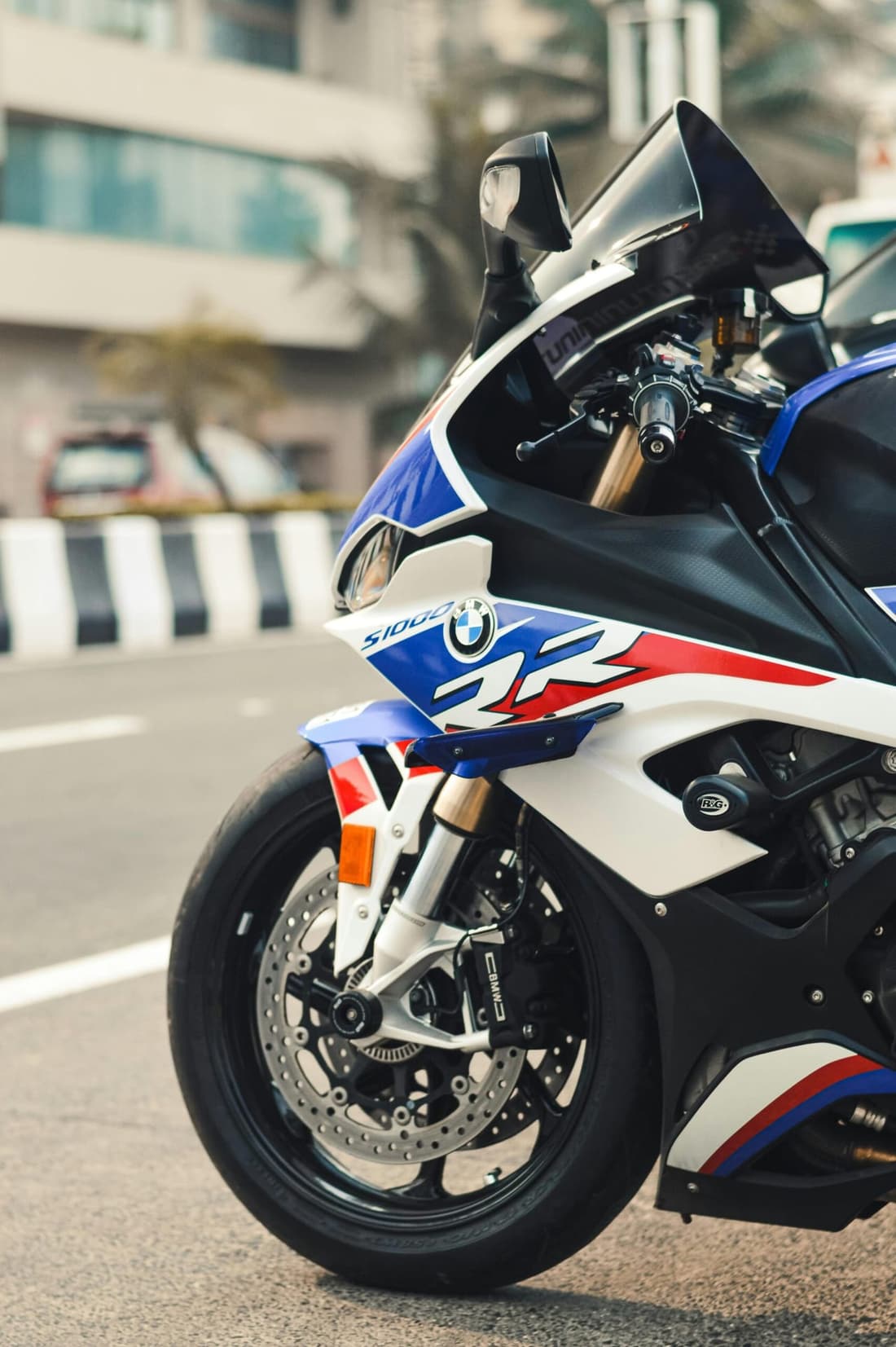 Close-up of a BMW S1000RR motorcycle parked on the street, showcasing its sleek design and glossy finish.