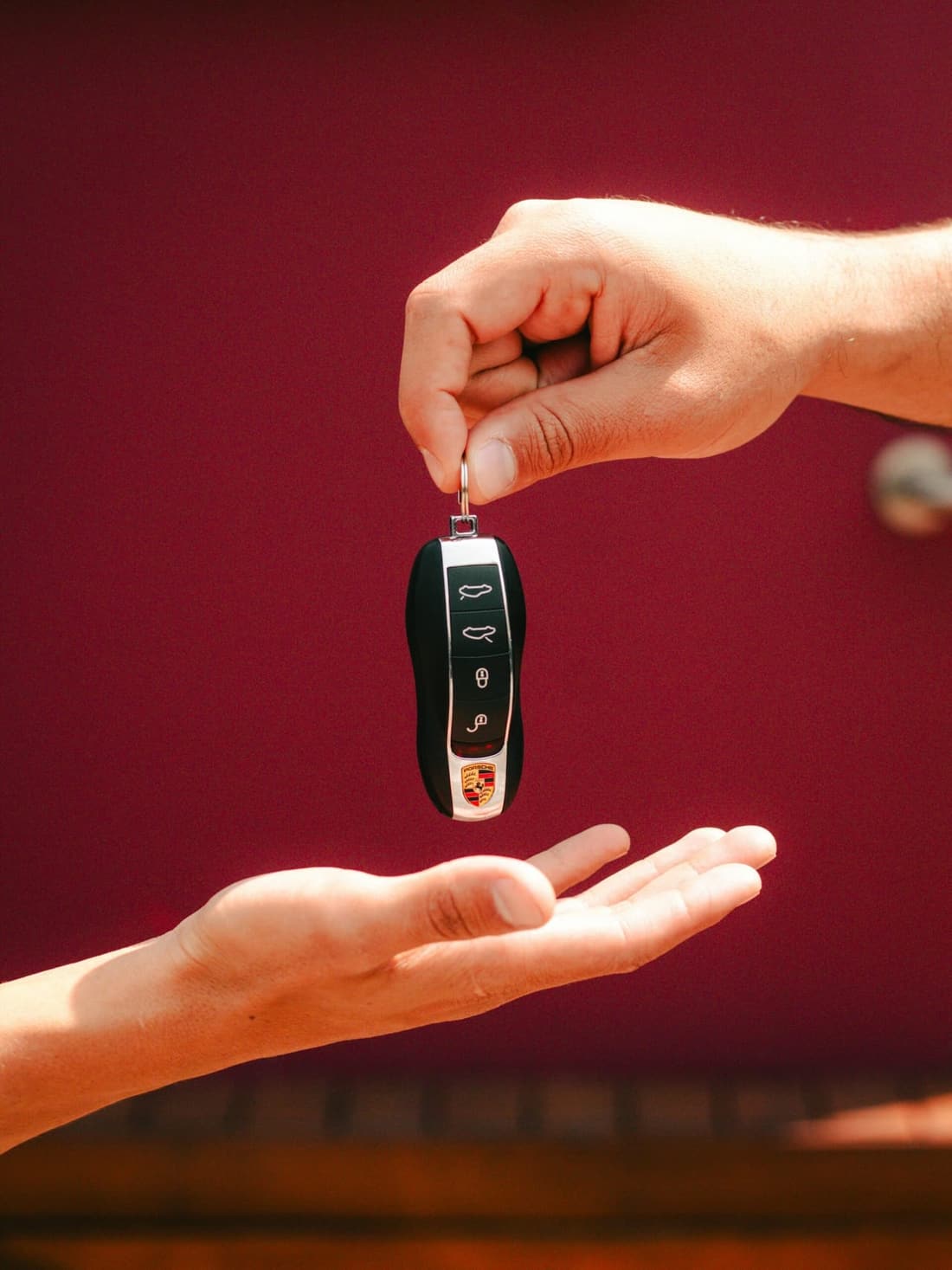 A clean Porsche key being handed over, symbolizing the impact of car detailing on resale value – Premier Detailing, West Plains MO.
