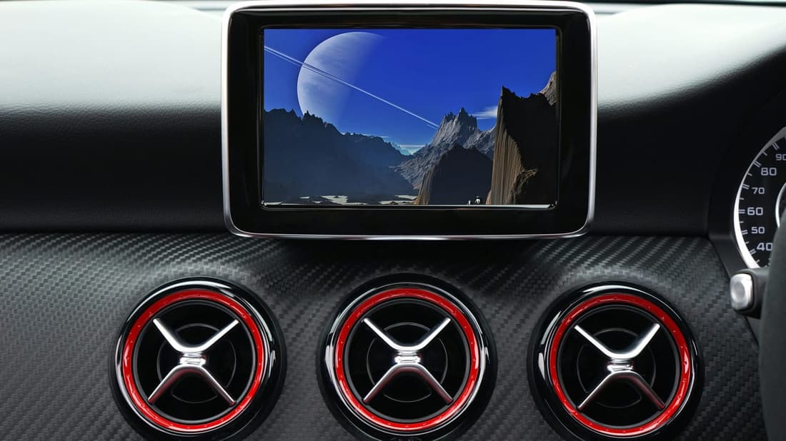 Close-up of a car's air vents and infotainment screen, emphasizing a sleek, clean dashboard with a futuristic display.