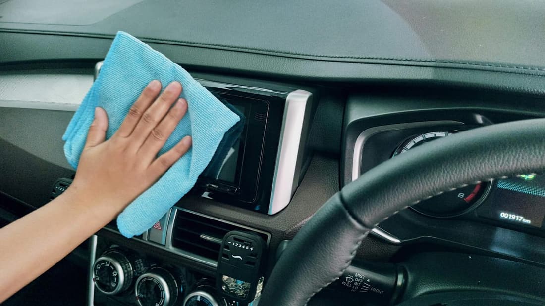 Premier Detailing team cleaning car dashboard with blue microfiber towel