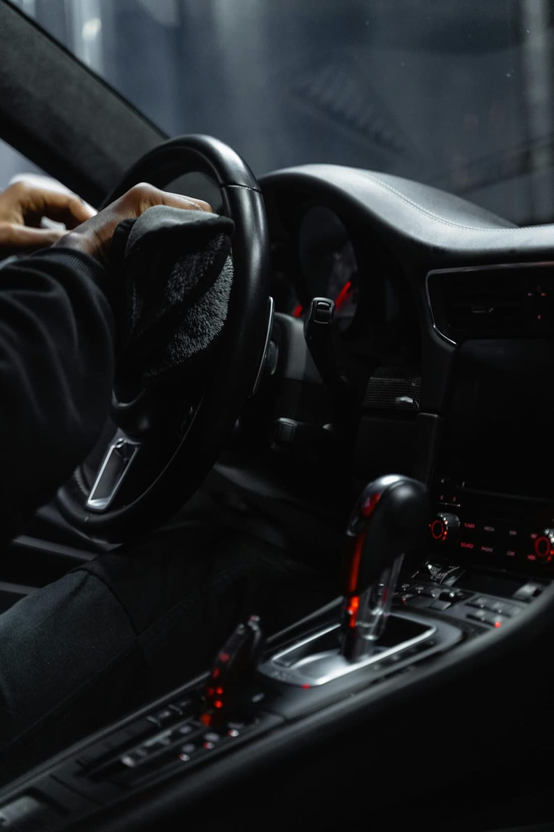 "A Premier Detailing technician carefully wipes down a vehicle's steering wheel, ensuring a spotless and sanitized interior."