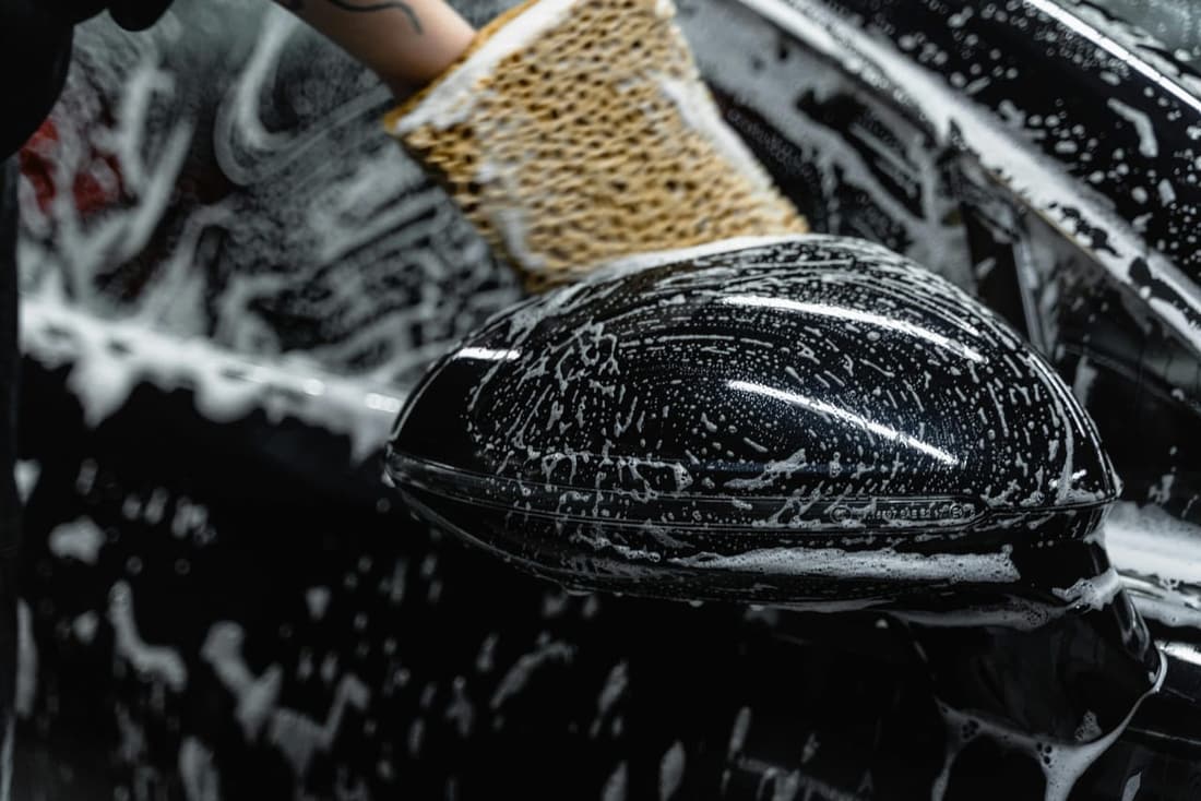 "Black car covered in rich car shampoo during a professional wash, showcasing meticulous attention to detail by Premier Detailing in West Plains, MO."