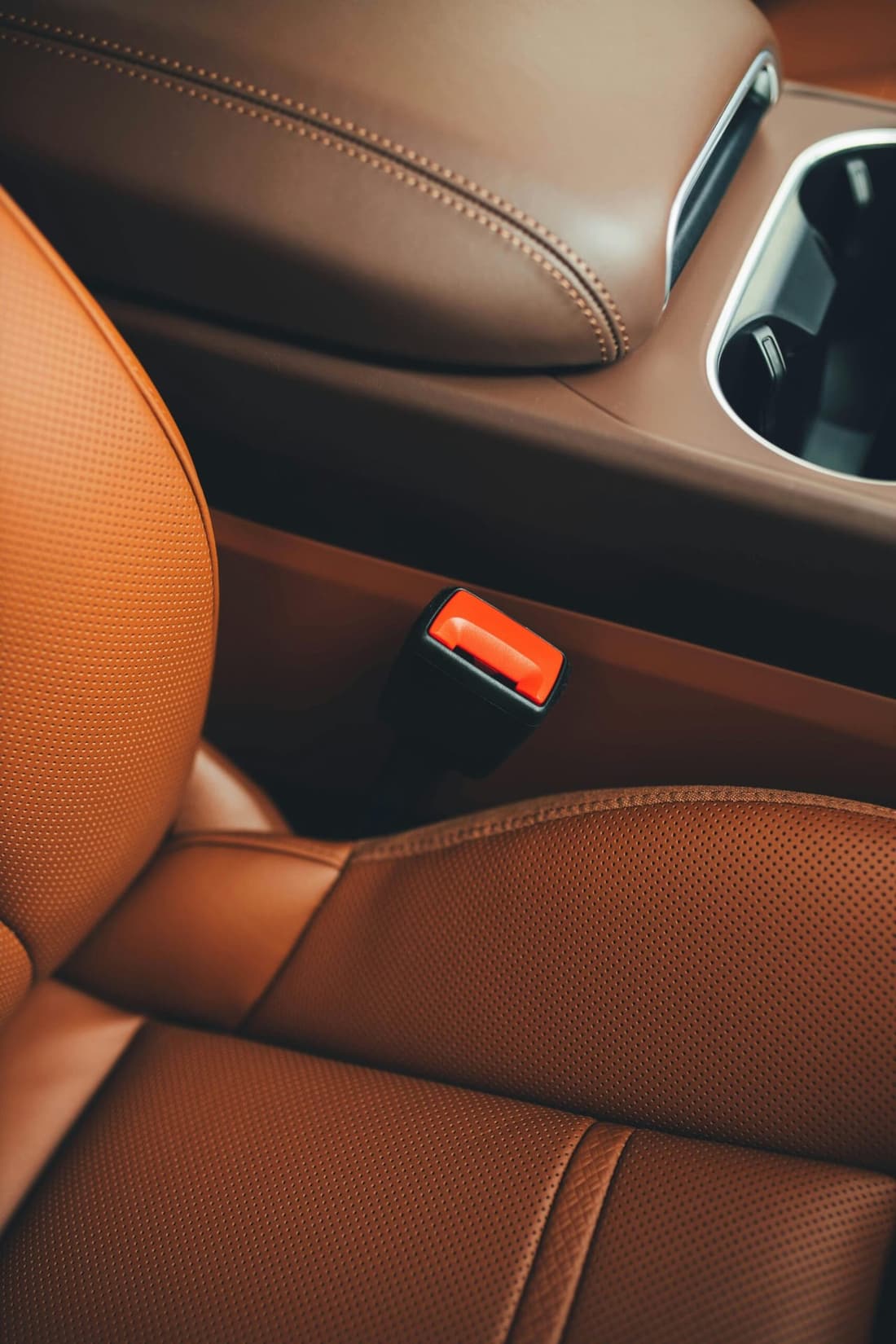 Brown car seat with seat belt buckle close-up, showing detailed interior cleaning