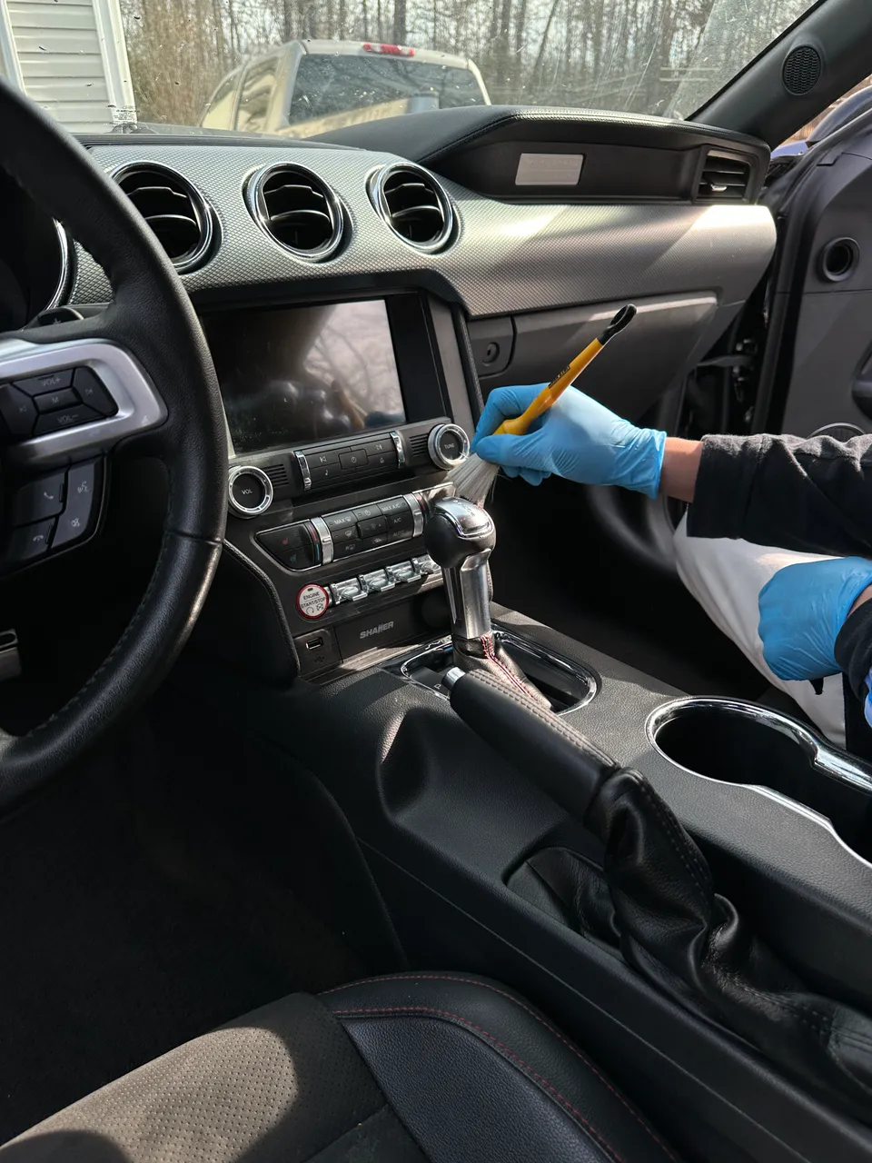 A Premier Detailing technician deep-cleaning a car interior with a detailing brush in West Plains, MO